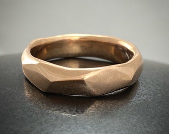 May include: A gold ring with a faceted, geometric design. The ring is made of a smooth, polished metal.