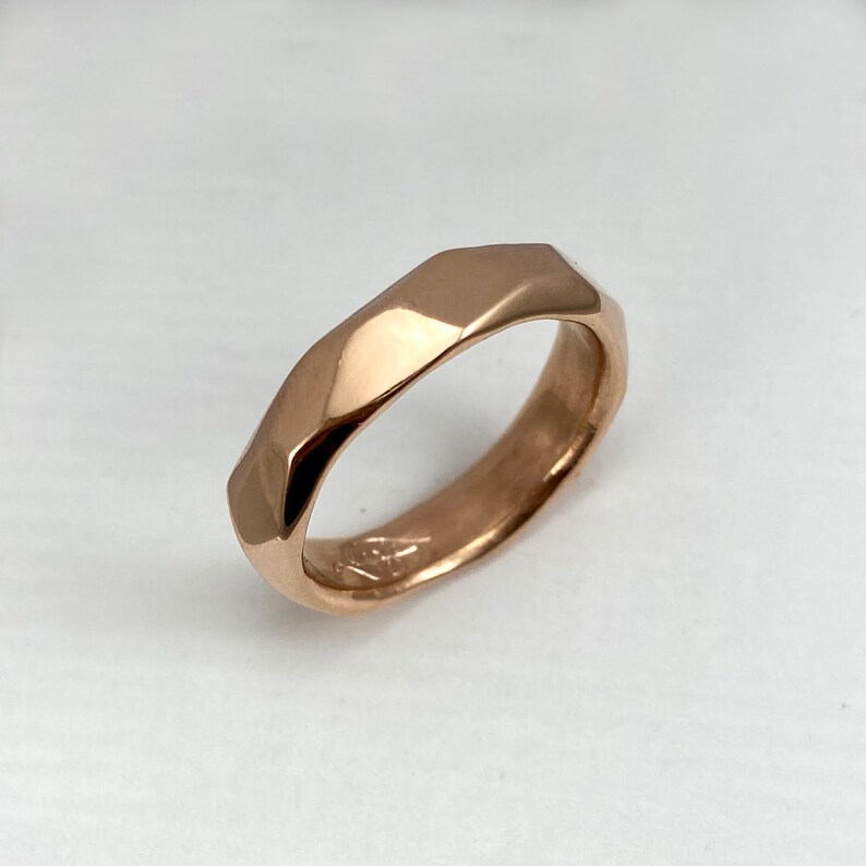 Puede incluir: Un anillo de banda de oro rosa con un dise&ntilde;o facetado y geom&eacute;trico.