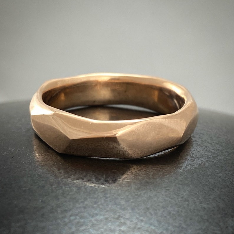 Puede incluir: Un anillo de oro con un dise&ntilde;o facetado y geom&eacute;trico. El anillo est&aacute; hecho de un metal liso y pulido.