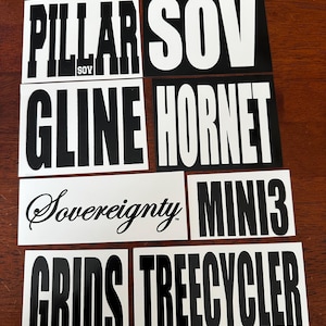 May include: A collection of rectangular stickers featuring black and white text designs. The stickers display the words PILLAR SOV, SOV, GLINE, HORNET, Sovereignty, MINI3, GRIDS, and TREECYCLER in various bold, sans-serif, and script fonts.
