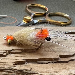 May include: Two orange and white fly fishing lures with black beads and brown feathers.