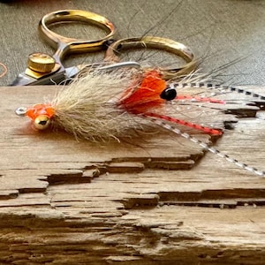 Op de afbeelding: Twee oranje en witte vliegenvisluren met zwarte accenten op een houten oppervlak.