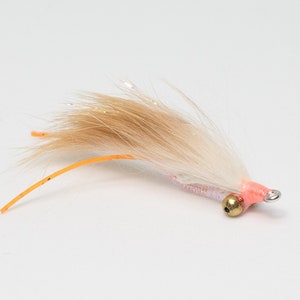 May include: A white and brown fly fishing lure with a pink head and a gold bead. The lure has a long orange tail.