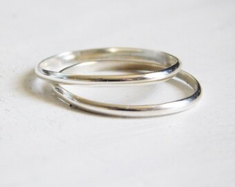 May include: Two silver stacking rings, one slightly larger than the other, are shown on a white background.