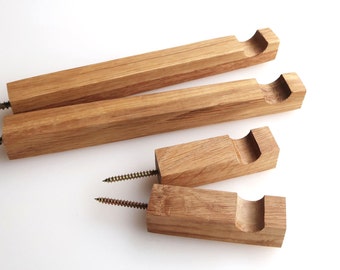May include: Four light brown wooden wall hooks of varying lengths, each featuring a square profile, a semi-circular notch at one end, and a metal screw protruding from the opposite end for mounting purposes, showcasing a natural wood grain texture.