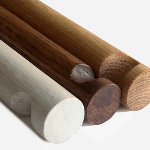 Puede incluir: Tres clavijas de madera, una gris claro, una marrón oscuro y una marrón claro, con extremos redondeados.