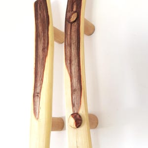 Peut inclure: Deux poignées de porte de placard en bois avec une finition en bois naturel et un grain de bois brun foncé. Les poignées sont courbées et ont un bouton rond à l'extrémité.