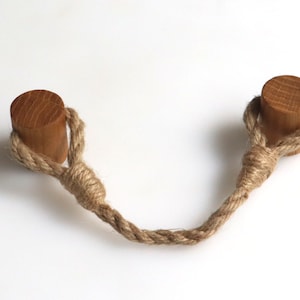 May include: Two wooden knobs connected by a length of natural jute rope. The rope is tied in a knot in the center.