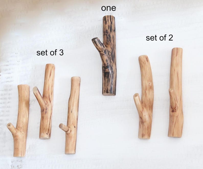 Puede incluir: Una colecci&oacute;n de ganchos de pared de madera con forma de ramas de &aacute;rbol. El juego de 3 presenta madera de color marr&oacute;n claro, el gancho individual es marr&oacute;n oscuro con vetas negras y el juego de 2 consta de ganchos de madera clara con vetas.