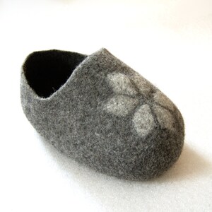 May include: A grey felt slipper with a white flower design.