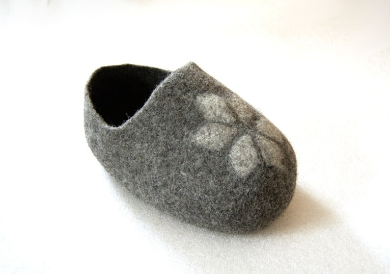 May include: A grey felt slipper with a white flower design.