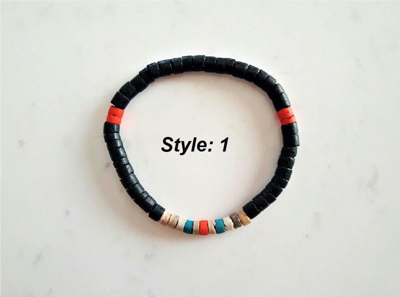 Pode incluir: Uma pulseira circular composta por pequenas contas cil&iacute;ndricas de cor preta mate. O design apresenta duas contas cor de laranja, uma conta azul brilhante, uma conta bege e uma conta cinzenta intercaladas entre as pretas. O texto Style: 1 &eacute; vis&iacute;vel.