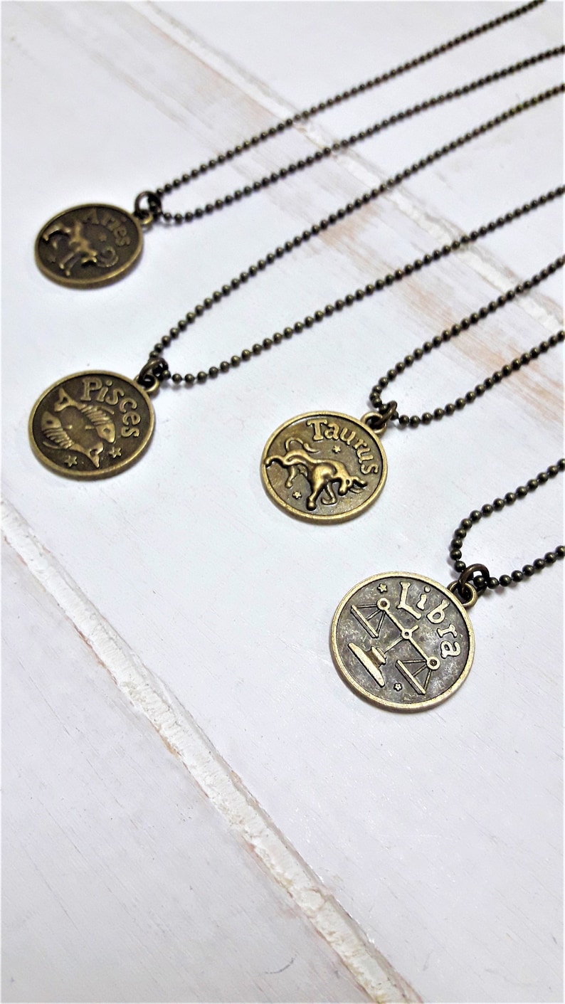 May include: Four gold-toned necklaces with zodiac signs. The signs are Aries, Pisces, Taurus, and Libra.