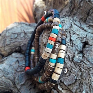 Pode incluir: Tr&ecirc;s pulseiras feitas de pequenas contas planas e circulares nas cores preta, castanha, bege, turquesa e vermelha. As pulseiras est&atilde;o numeradas 1, 2 e 3, com padr&otilde;es de cores alternados de contas com aspeto de madeira e acabamento mate.