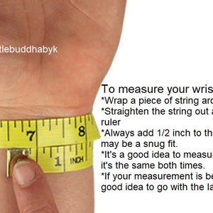 Pode incluir: Uma fita m&eacute;trica amarela enrolada em um pulso com o texto Littlebuddhabyk e instru&ccedil;&otilde;es sobre como medir o pulso, incluindo adicionar 1/2 polegada para um ajuste correto, com os n&uacute;meros 6, 7 e 8 vis&iacute;veis.