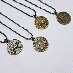 May include: Four gold-toned zodiac necklaces with chain links. The necklaces feature pendants with the astrological signs of Aries, Taurus, Pisces, and Libra.