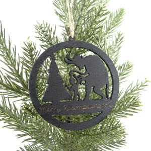 May include: Black wooden Christmas ornament with a silhouette of Krampus, a Christmas demon, and a child. The ornament is round and has the text "Merry Krampusnacht" inscribed on the bottom.