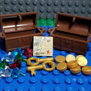 May include: Two brown wooden treasure chests with lids open, revealing a map, two gold keys, gold coins, and red, green, and clear gems.