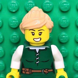May include: A Lego minifigure with blonde hair, a green shirt, a brown belt, and a white collar. The minifigure is smiling and has a yellow face.