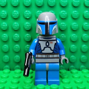 May include: A Lego minifigure of a character from the Star Wars franchise. The figure is primarily blue, gray, and white, with a black weapon. The figure is standing on a green Lego baseplate.