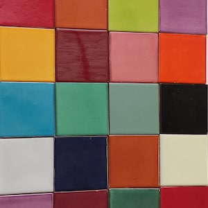 May include: A collection of 18 square ceramic tiles in various colors, including red, orange, yellow, green, blue, purple, brown, black, and white.