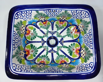 May include: A square ceramic sink with a blue rim and a floral design in shades of blue, green, red, and yellow.