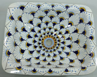 May include: A white ceramic sink with a blue and yellow floral design. The sink has a circular drain in the center.