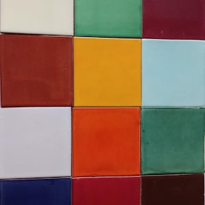 May include: A grid of sixteen square ceramic tiles in various colors. The colors include white, green, burgundy, red, yellow, light blue, orange, dark green, white, blue, and brown. The tiles have a glossy finish.
