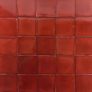 Puede incluir: Una hoja de 25 pequeñas baldosas cuadradas de cerámica roja. Las baldosas están dispuestas en un patrón de cuadrícula.