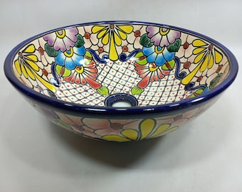 May include: A ceramic sink with a colorful floral design. The sink is white with blue, yellow, pink, red, and green flowers. The sink has a blue rim and a drain hole in the center.