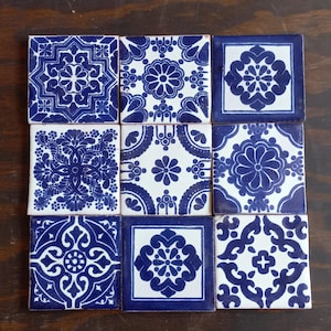 May include: A collection of nine square ceramic tiles arranged in a three-by-three grid. Each tile features a distinct blue and white pattern, showcasing intricate floral, geometric, and symmetrical motifs printed on a smooth, glossy surface.