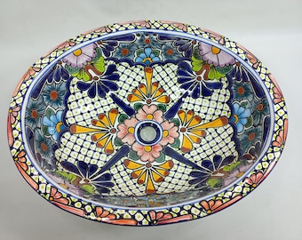 May include: Oval ceramic sink with a colorful floral pattern in shades of blue, pink, yellow, green, and brown. The sink has a white background with a geometric pattern.