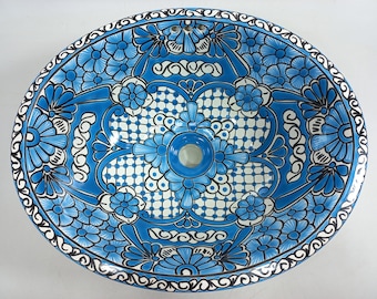 May include: A blue and white ceramic sink with a floral design. The sink is oval shaped and has a drain hole in the center.