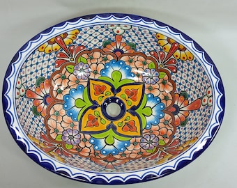 May include: A colorful ceramic oval sink with a floral design. The sink has a blue and white border with a scalloped edge. The floral design features a variety of colors, including red, orange, yellow, green, blue, and purple.