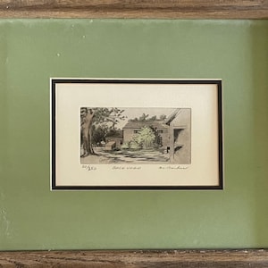 May include: Framed black and white etching of a backyard scene. The artwork, numbered 20/250, depicts a house, trees, and the word "Backyard". The etching is set within a black mat and a green frame, encased in a wooden frame.