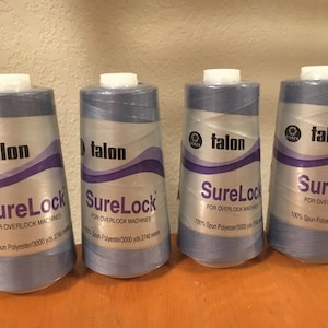 May include: Four spools of blue thread labeled "Talon SureLock" for overlock machines. Each spool contains 3000 yards of 100% spun polyester thread.