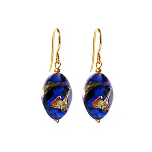 May include: A pair of gold dangle earrings with blue glass beads. The beads have a swirl pattern and contain dried flowers.