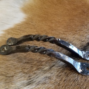 May include: Two black metal twisted handles with a hammered finish. The handles are approximately 6 inches long and have a rounded shape.