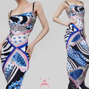 May include: A patterned maxi dress with thin black straps. The dress features a mix of black and white zebra stripes, blue floral patterns, and pink accents. The dress has a pleated design and a unique asymmetrical hemline.