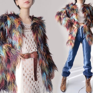 May include: A colorful faux fur jacket with a shaggy texture. The jacket features a mix of blue, yellow, orange, and purple hues. The jacket is open-fronted and has long sleeves. A brown leather belt is worn with the jacket.