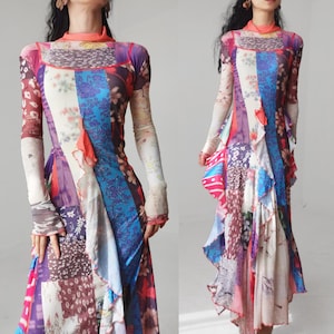 May include: A long-sleeved maxi dress featuring a vibrant patchwork design with various floral and abstract patterns in shades of blue, pink, white, and brown. The garment includes a high mock neck collar and a vertical ruffled trim along the front.