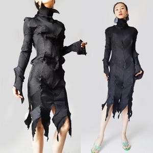 Puede incluir: Dos imágenes de un vestido negro de vanguardia con cuello alto y mangas largas. El vestido presenta un diseño plisado con recortes geométricos y una falda hasta la rodilla con aberturas asimétricas. La tela tiene una apariencia texturizada y acanalada.