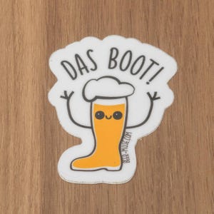 May include: White sticker featuring a cartoon beer glass with arms and legs. The glass is wearing a white chef's hat and has a happy face. The text "DAS BOOT!" is above the glass. The text "BEER-MUSE.COM" is below the glass.