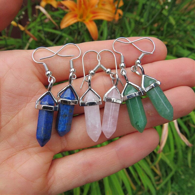 May include: Four pairs of silver dangle earrings with crystal point charms. The charms are in shades of blue, pink, and green.