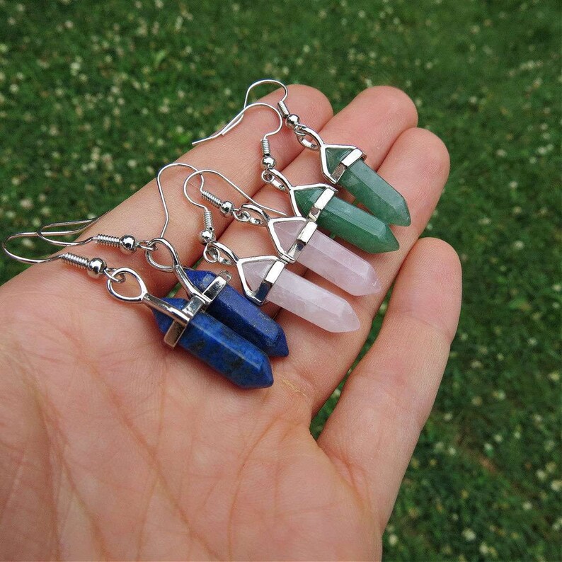 May include: Three pairs of silver dangle earrings with crystal point charms. The charms are in shades of green, pink, and blue.