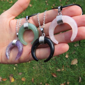 Pode incluir: Quatro colares de lua crescente com corrente e fecho de prata. As luas s&atilde;o feitas de pedras de diferentes cores: verde, roxo, preto e rosa.