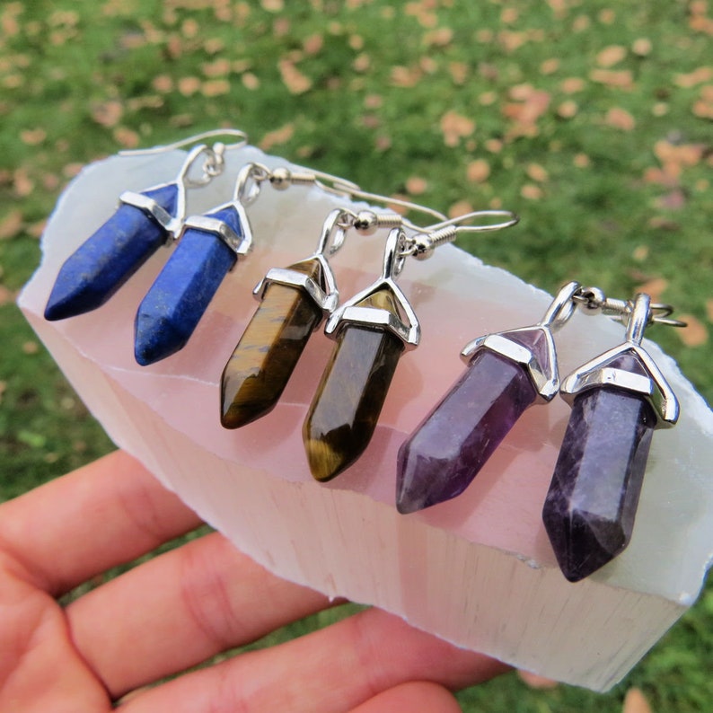 May include: Four pairs of silver earrings with crystal point pendants. The crystals are blue, brown, and purple.