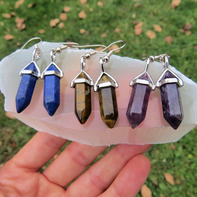 May include: Six pairs of silver dangle earrings with crystal point charms. The charms are in four colors: blue, brown, purple, and green.
