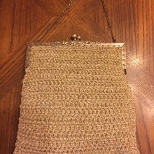 May include: A beige crocheted purse with a silver clasp and chain strap.
