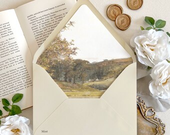 May include: A cream-colored envelope with a pointed flap, featuring an interior liner printed with a landscape painting of trees and fields. The word Mist is printed on the lower left corner. The envelope is surrounded by white roses and wax seals.
